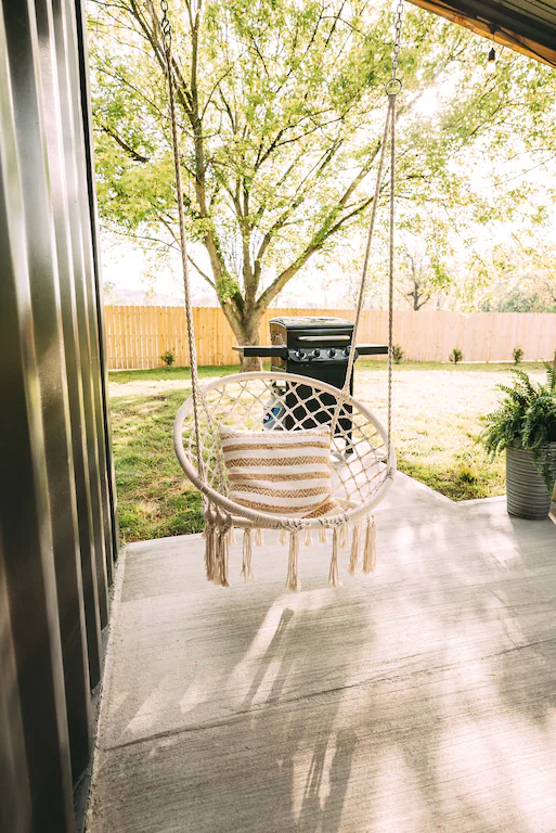 Our rear patio is covered and equipped with nice patio chairs, a hot tub, and a macrame swing.
