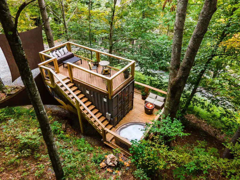 The Tiny Bunker has two decks with a hot tub, a fire table, an eating space, a lounge area, and a tree that is surrounded by summer/spring and winter mountain VIEWS!