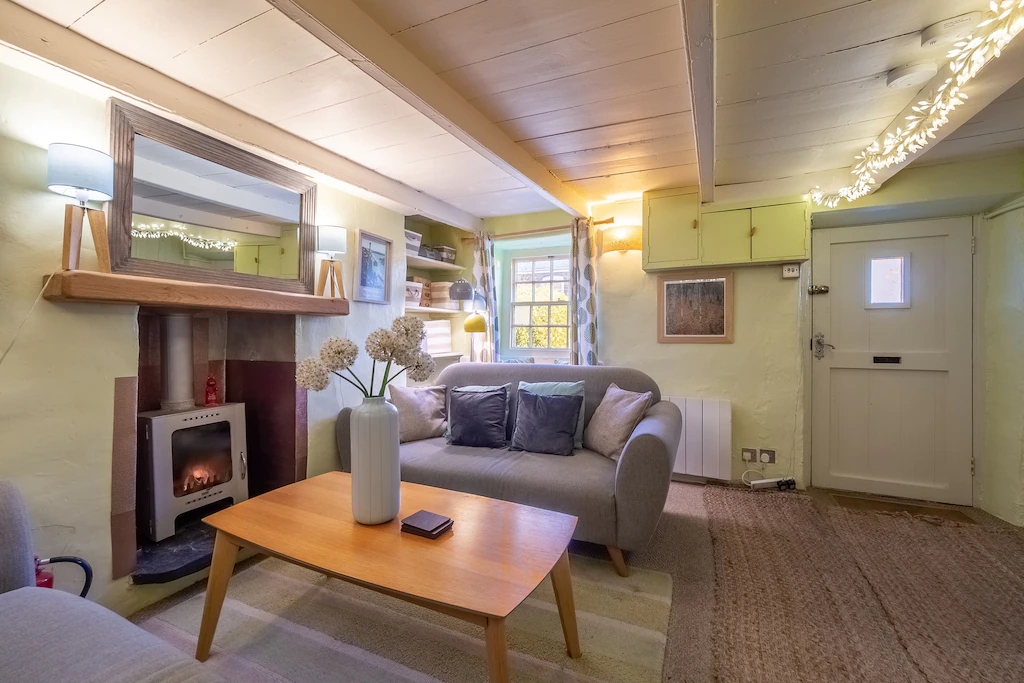 A comfortable room with a television, steps to the first floor, a latch door, and a modern wood burning stove.