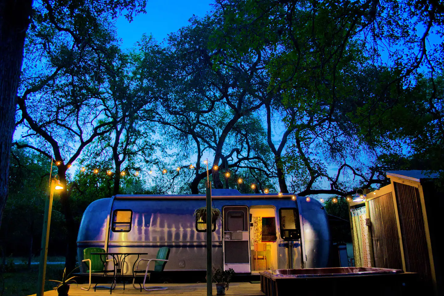 The Airstream campsite offers it all: a charcoal grill, a hot tub, a deck, an outdoor dining table with an umbrella, a shaded tree grove, an outdoor shower, and a fire ring with seats!