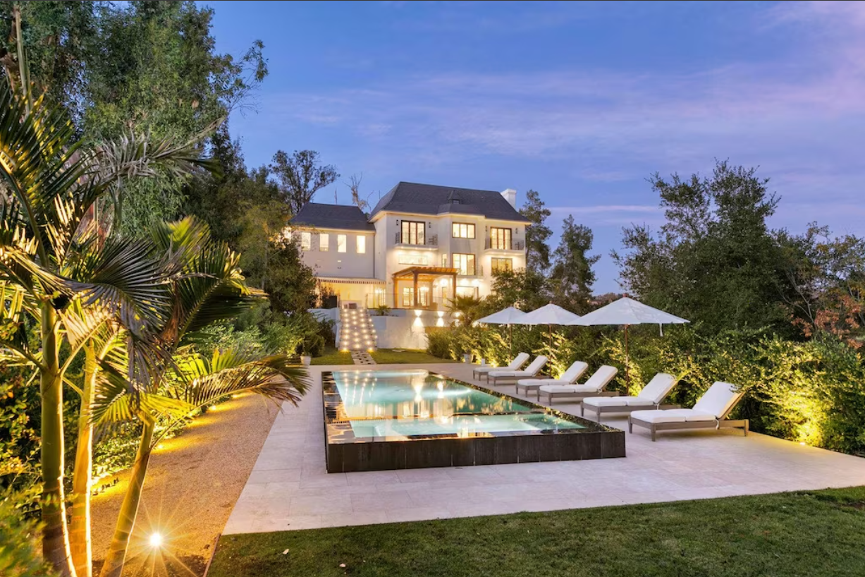 This stunning Chateau's backyard features lush California foliage, a zero-edge pool, and a patio area.
