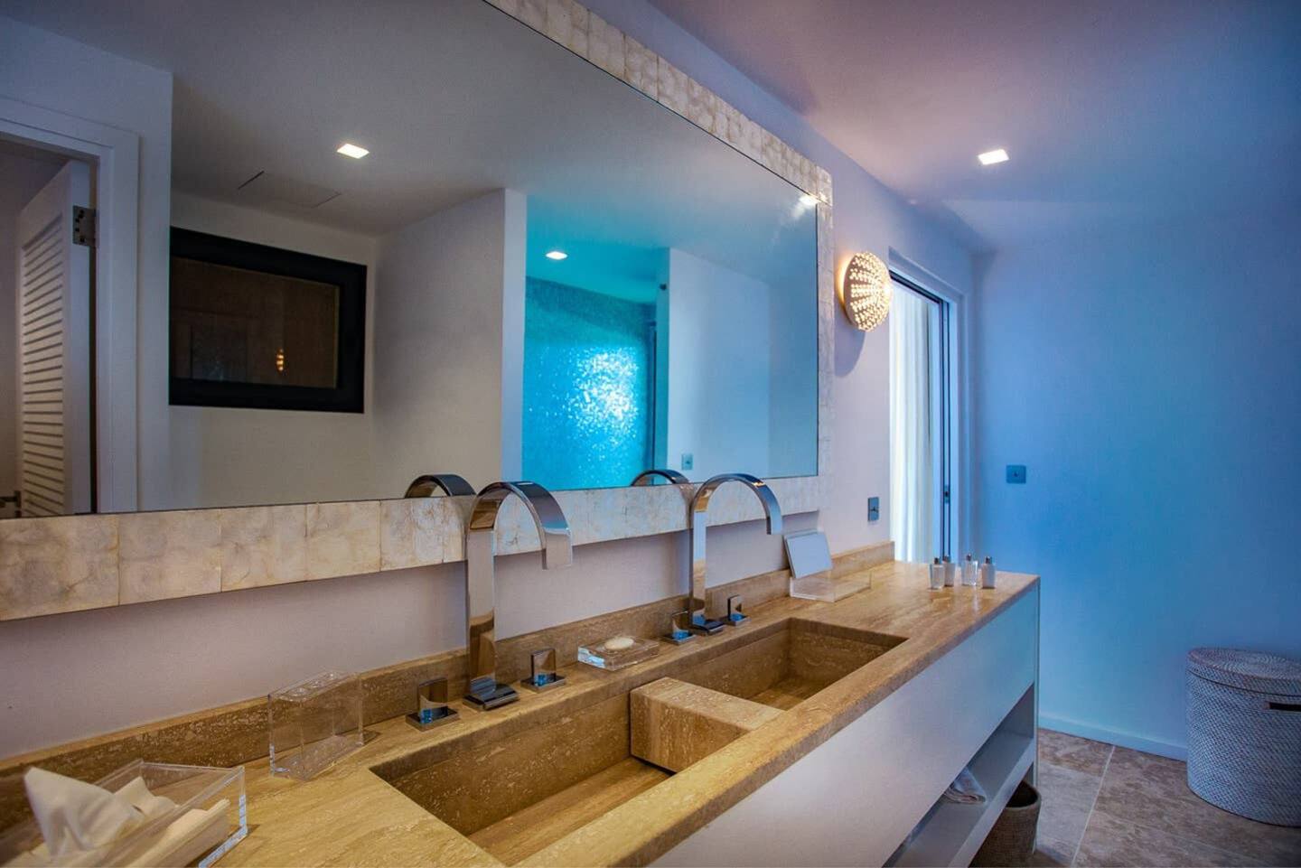 A spacious and luxurious bathroom featuring two sinks, a wide mirror, modern fixtures, and a soothing color palette.