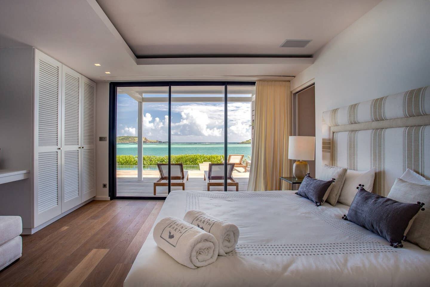 A cozy and well-appointed bedroom with direct access to stunning beach views, featuring a comfortable bed, stylish furnishings, and a calming ambiance.
