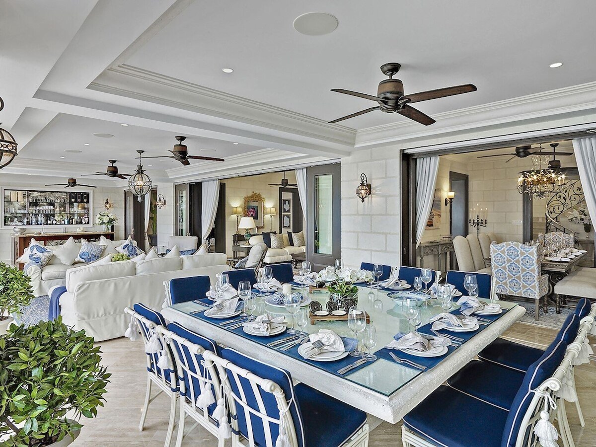A sophisticated dining area adorned with a large, polished table, stylish chairs, and an elaborate chandelier.