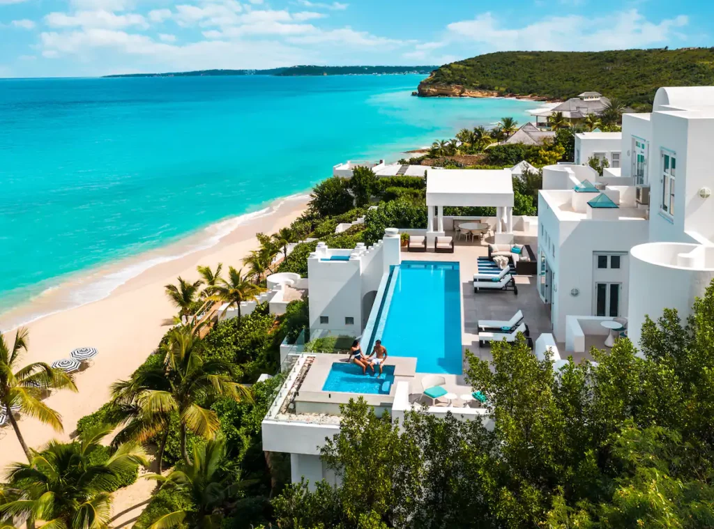 Aerial view of a luxurious villa nestled by the beach, showcasing stunning beachfront location and architecture.